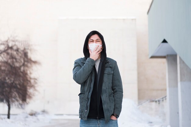 Front view of man with medical mask posing outside