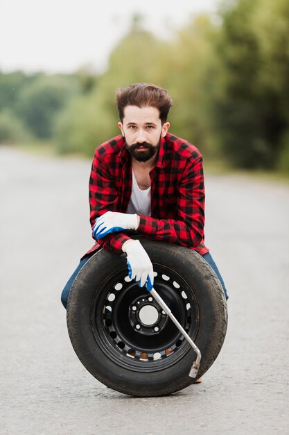 Front view of man with tire and wrench