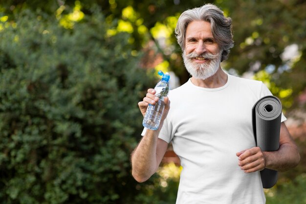 Front view man with water and yoga mat