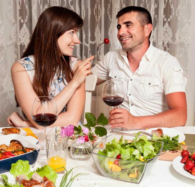 Front view of man and woman at dinner table with wine and food