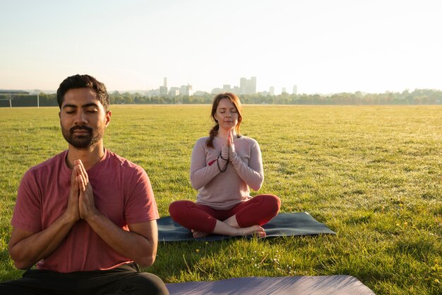 ヨガマットで屋外で瞑想する男女の正面図