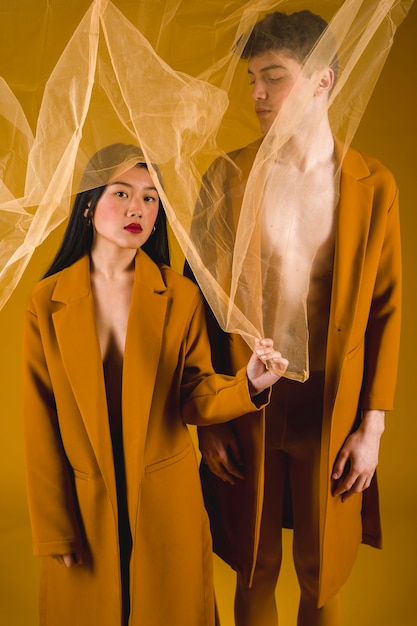 Front view man and woman posing with a transparent fabric