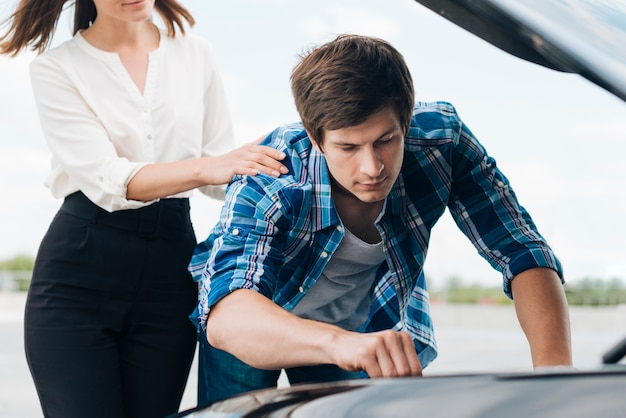 Front view of man working on car engine