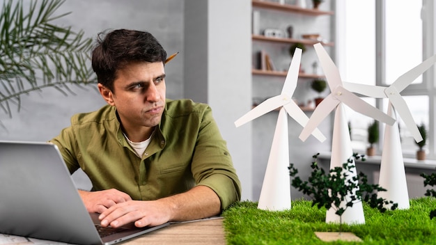 ノートパソコンで環境にやさしい風力発電プロジェクトに取り組んでいる男性の正面図