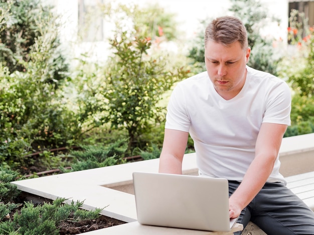 Front view of man working on laptop outdoors