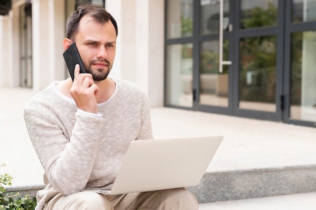 Free photo front view of man working on laptop outdoors