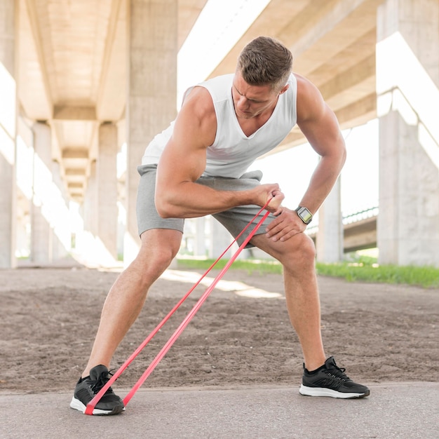 Free photo front view man working out with a red stretching band