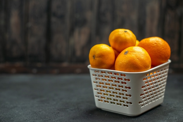 Front view mandarines and oranges in plastc basket on dark free space