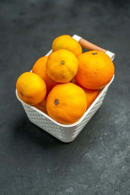 Front view mandarines and oranges in plastc basket on dark free space