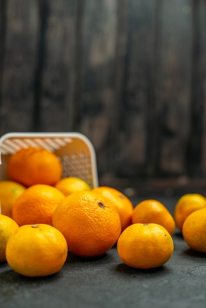 Front view mandarines and oranges scattered from plastc basket on dark free space