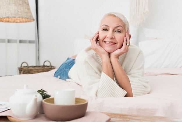 Front view of mature happy woman smiling and posing in bed