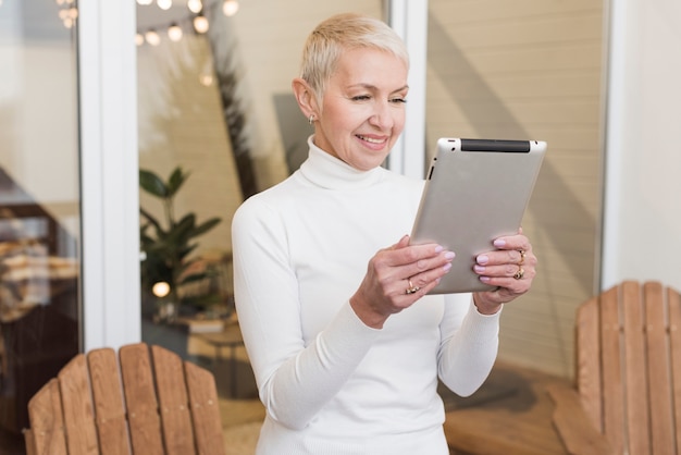 Front view mature woman looking on her tablet indoors