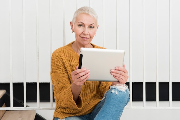 Front view of mature woman smiling and holding tablet