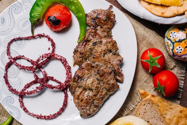 Kebab del basturma della carne di vista frontale con il pomodoro e il peperoncino sulla griglia con la cipolla in sumac