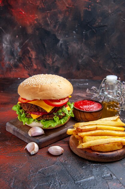 Front view meat burger with cheese salad and tomatoes on the dark background