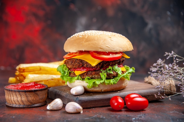Мясной бургер, вид спереди, сырный салат и помидоры на темном столе