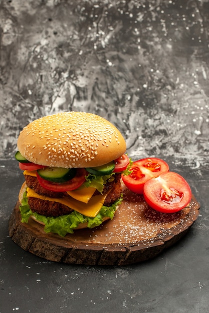 Вид спереди мясной бургер с овощами и сыром на темной поверхности сэндвич-булочка фаст-фуд