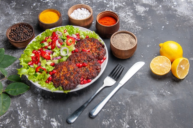 Foto gratuita cotolette di carne vista frontale con insalata fresca e condimenti