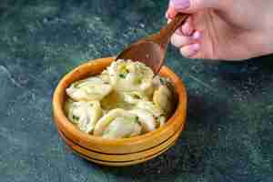 Free photo front view meat dumplings with female putting wooden spoon into it on dark surface
