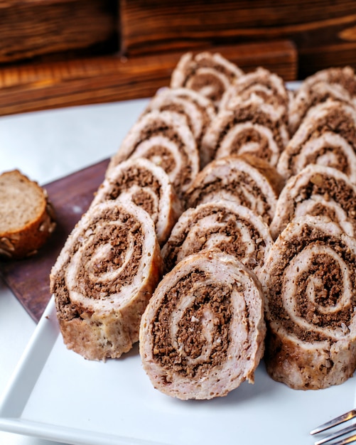 Front view meat rolls inside white plate on the brown floor