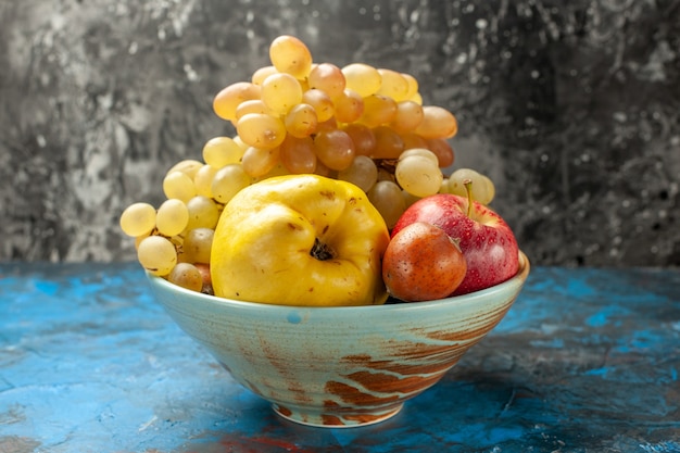 Vista frontale frutti dolci mela cotogna e uva all'interno della piastra sullo sfondo blu dieta salute vitamina foto matura gustosa