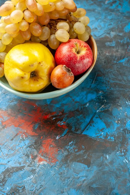 Вид спереди спелые фрукты айва яблоко и виноград внутри тарелки на синем фоне здоровая диета витамин спелые фото вкусно