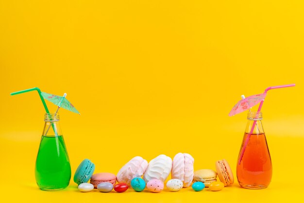 A front view meringues and macarons along with cocktails on yellow, cake biscuit confectionery