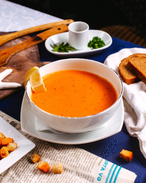 A front view merji soup eastern dish orange which is served along with lemon on the blue floor