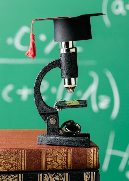 Front view of microscope on stack of books with academic cap