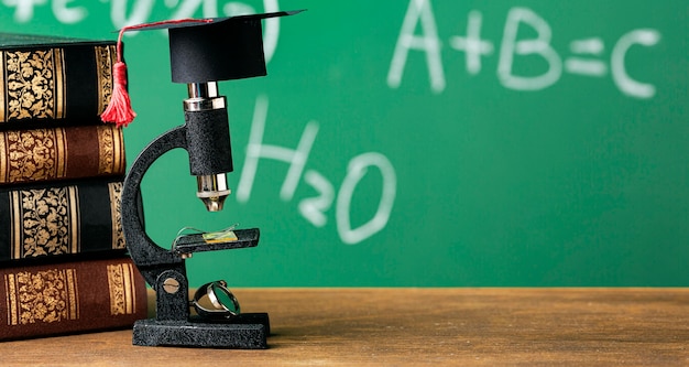 Free photo front view of microscope with academic cap and copy space