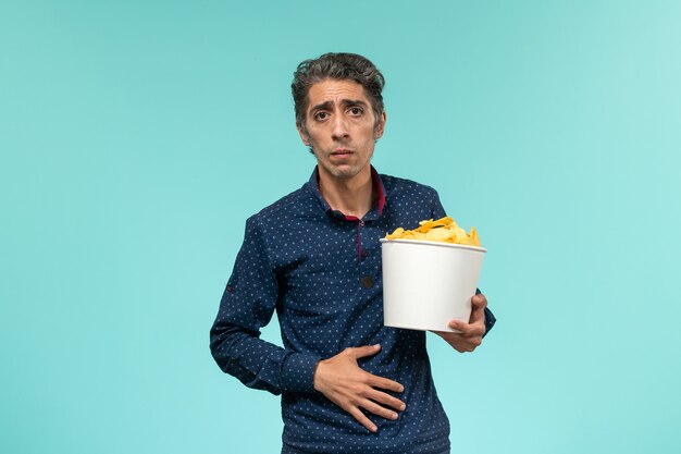 青い表面にcipsを食べる中年男性の正面図