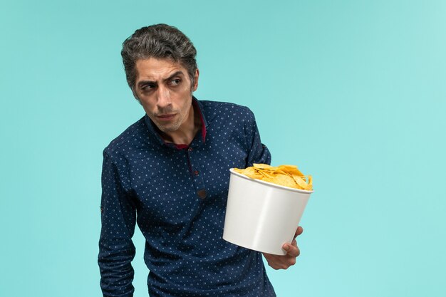 Front view middle-aged male holding basket with potato cips on blue surface