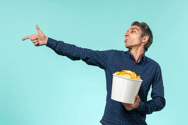 Front view middle-aged male holding potato cips on blue surface