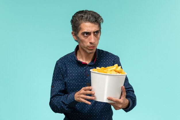 Front view middle-aged male with basket full of potato cips on blue surface