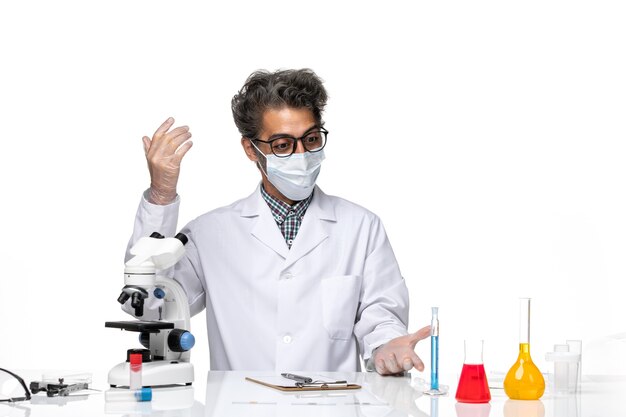 Front view middle-aged scientist in special suit sitting and writing notes