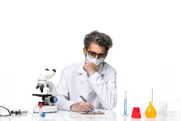 Front view middle-aged scientist in special suit sitting writing notes