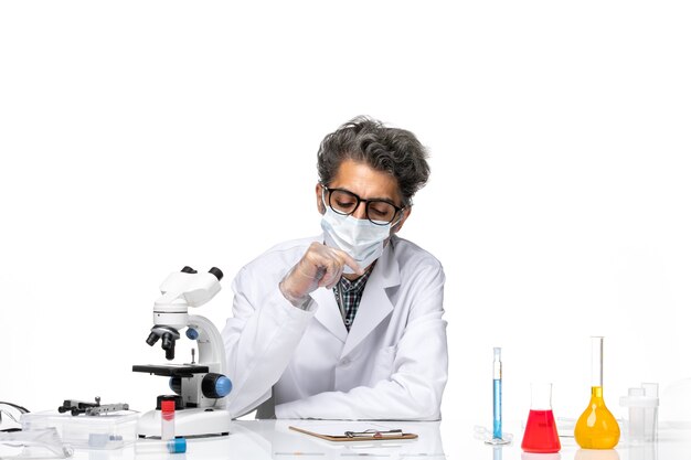 Front view middle-aged scientist in special suit sitting writing notes