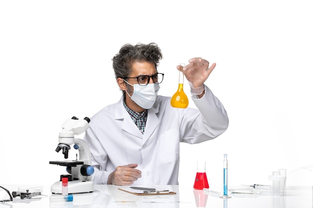Вид спереди ученый средних лет в специальном костюме, работающий с растворами