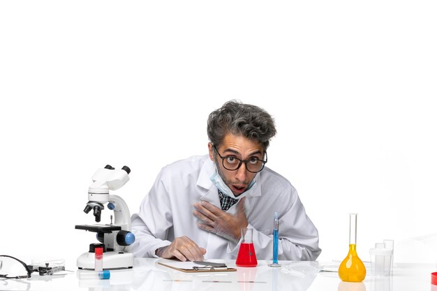 Front view middle-aged scientist in special white suit smelling red solution and feeling bad