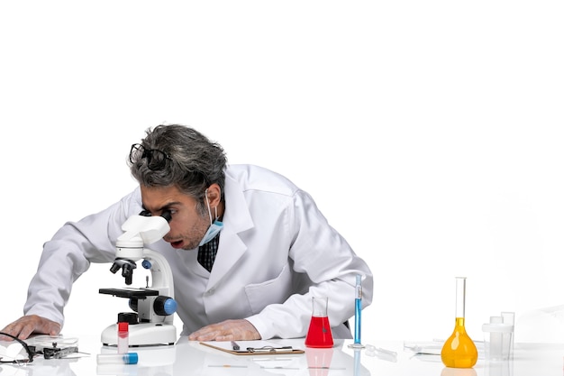 顕微鏡を使用して特別な白いスーツを着た中年の科学者の正面図