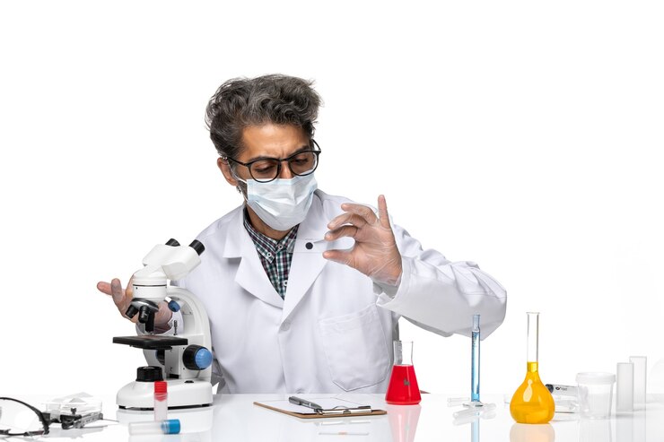 Free Photo front view middle-aged scientist in white medical suit checking little sample through microscope