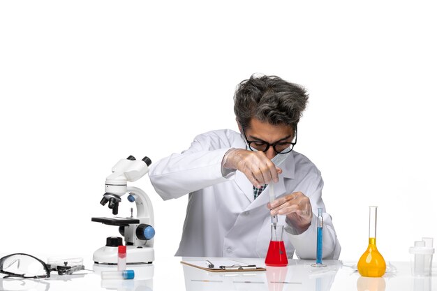Вид спереди ученого средних лет в белом медицинском костюме, заполняющего инъекцию раствором