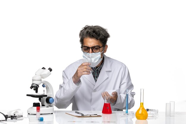 Front view middle-aged scientist in white medical suit holding empty flask