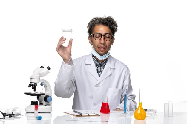 Front view middle-aged scientist in white medical suit holding empty flask