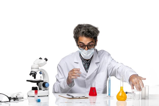 Front view middle-aged scientist in white medical suit holding flask