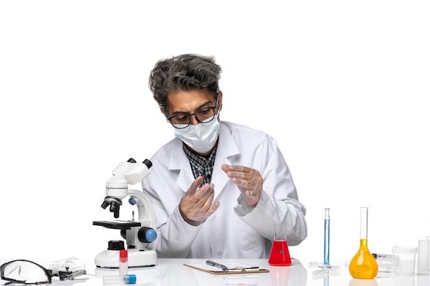 Front view middle-aged scientist in white medical suit holding little sample