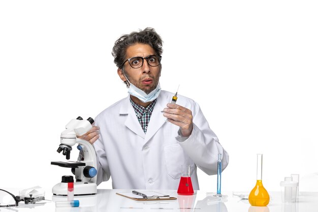 Front view middle-aged scientist in white medical suit preparing injection