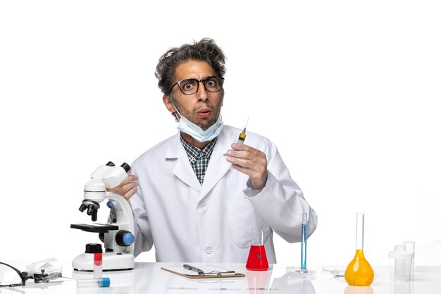 Вид спереди ученый средних лет в белом медицинском костюме готовит инъекцию