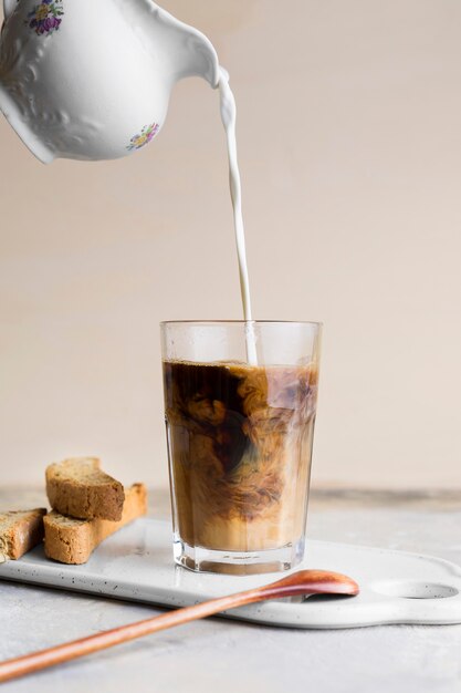 Front view milk being poured in frappe next to slices of bread with seeds