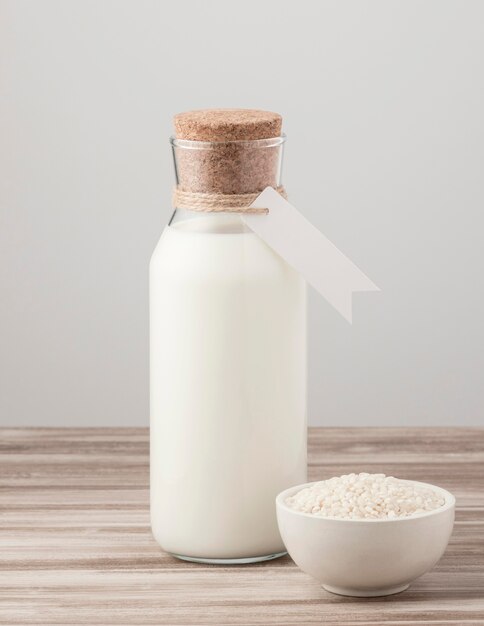 Вид спереди бутылки молока и миски риса